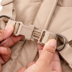 Close-up of beige harness buckle and adjustable strap with metal D-ring.