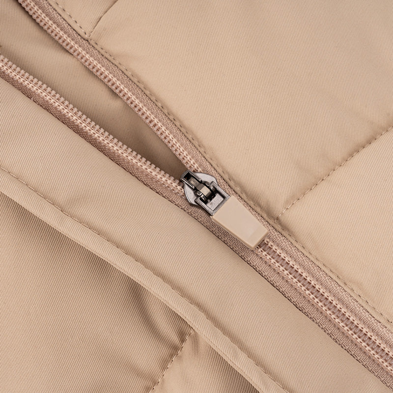Close-up of beige quilted dog vest showing durable zipper closure and stitched padding detail.
