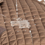 Water resistant brown quilted dog jacket with water beading on surface